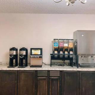 A self-service beverage station featuring coffee machines and drink dispensers on a kitchen counter.