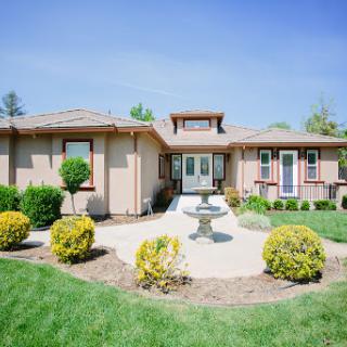A beautiful suburban home featuring a landscaped garden and a charming fountain.