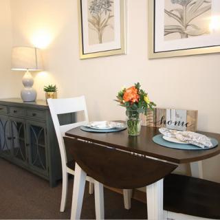 A cozy dining area with a small table set for two, adorned with a flower arrangement and surrounded by elegant decor.