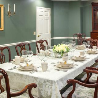 A formal dining room with a fully set table, featuring elegant china and silverware.