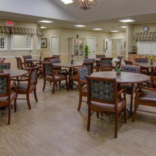 A spacious and well-lit dining area with multiple tables and chairs arranged neatly.