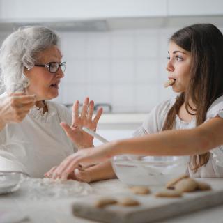 Two women having a conversation while preparing cookies in the kitchen.