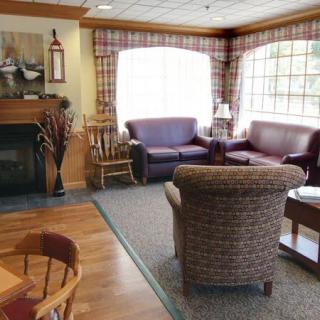 A cozy living room featuring two sofas, a fireplace, and large windows offering natural light.