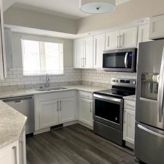 A newly renovated modern kitchen featuring white cabinets, stainless steel appliances, and ample natural light.