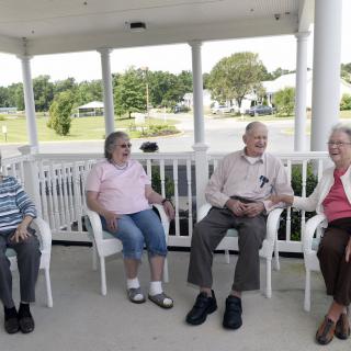 A group of seniors sitting and chatting on a porch.