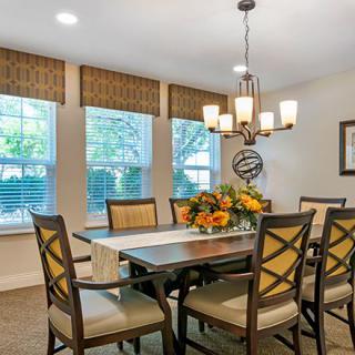A well-decorated dining room with a chandelier and large windows.