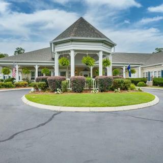 A building with a circular driveway and well-maintained landscaping under a partly cloudy sky.