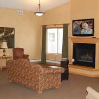 A cozy living room with a sofa, lamp, and a fireplace under a mounted television.