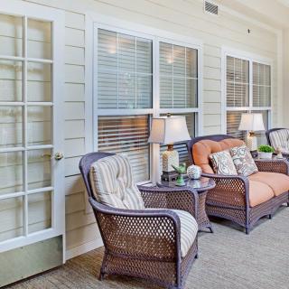 A cozy patio area with wicker furniture and soft cushions, illuminated by a lamp.