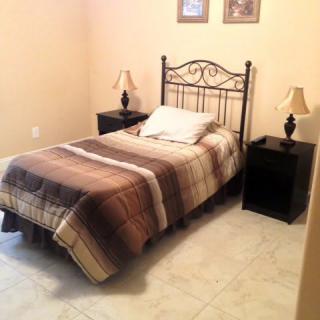 A cozy bedroom with a single bed, two nightstands, and lamps.