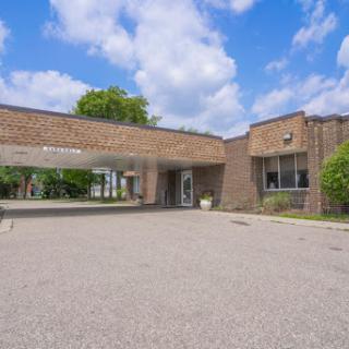 A spacious entrance of a modern brick building under a partly cloudy sky.