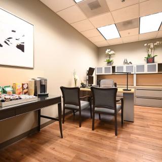 A modern office meeting room with a desk, chairs, and a coffee station.