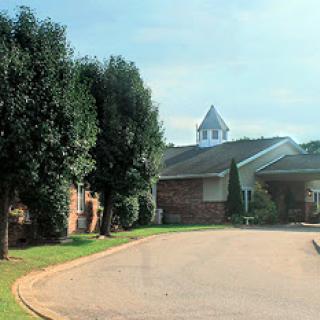 A peaceful scene featuring a building surrounded by trees and a winding road.
