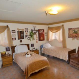 A cozy bedroom with two twin beds, decorated in warm brown tones and featuring traditional wall decor.