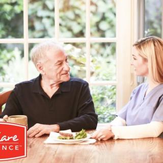 A caregiver assisting an elderly man during mealtime at home.