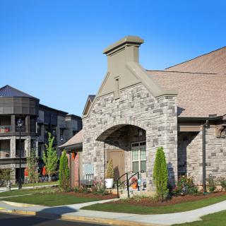 A modern residential building with a stone facade and well-maintained landscaping.