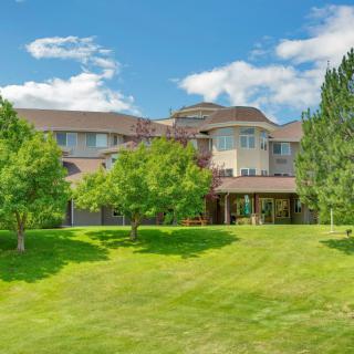 A beautiful house surrounded by a lush green lawn and trees under a clear blue sky.