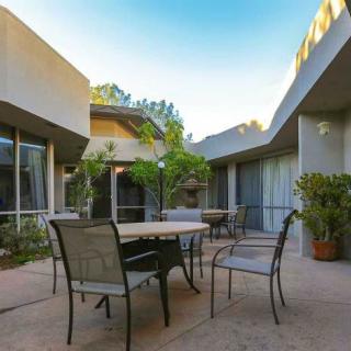 Modern patio area with a table, chairs, and surrounding plants.