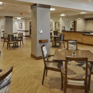 A spacious, modern dining area with wooden flooring and neatly arranged tables and chairs.