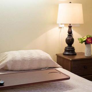 A cozy bedroom setup with a lamp and flower vase on the nightstand.