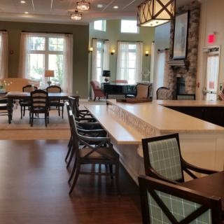 A spacious modern living area with a dining table, kitchen island, and large windows.