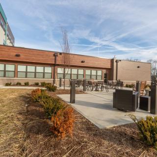 A modern building with an outdoor patio area and landscaped surroundings under a clear sky.