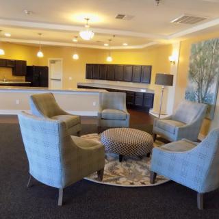 A modern lounge area with upholstered chairs and a round ottoman in the center.