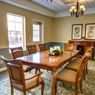 A well-furnished dining room with a wooden table, chairs, chandelier, and artwork.