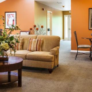 A cozy living room featuring a beige sofa, orange accent wall, and stylish decor.