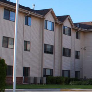 An exterior view of a multi-story apartment building under a clear blue sky.