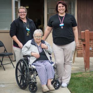 A moment of care and support, showcasing the bond between an elderly woman in a wheelchair and her dedicated caregivers.