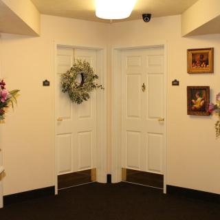 A hallway with two decorated doors, adorned with a wreath and artwork on the walls.