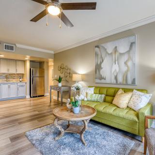 A modern living room with a green sofa, open kitchen, and stylish decor.