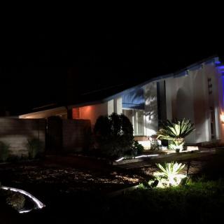 A modern house illuminated at night with stylish exterior lighting and landscaping.