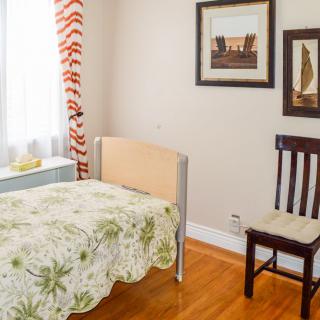 A cozy bedroom with a single bed, chair, and framed artwork on the wall.