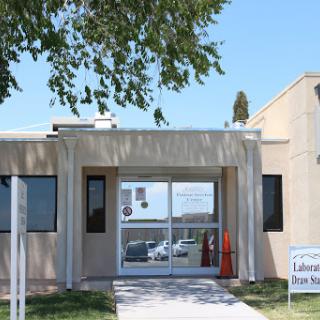Entrance of a modern building with large windows and a sign in front.