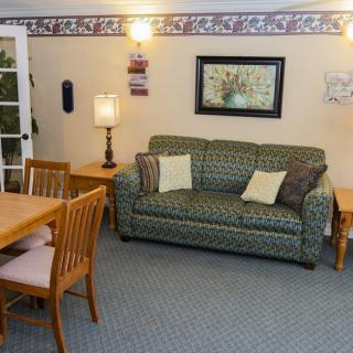 A cozy living room featuring a patterned sofa, dining area, and warm lighting.