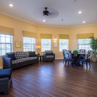 A spacious living area with comfortable seating and a dining table, well-lit by natural light from multiple windows.