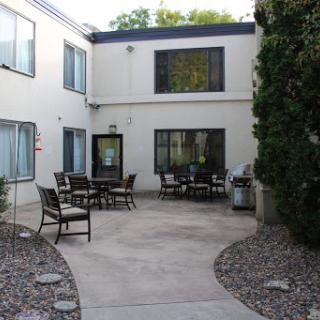 A peaceful courtyard with outdoor seating and a concrete pathway surrounded by greenery.