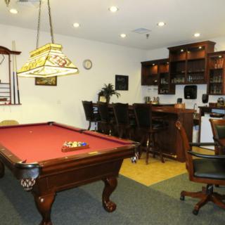 A cozy game room featuring a pool table and a bar area.