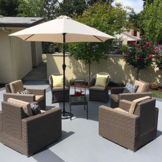 A cozy outdoor patio setup with chairs, cushions, and a large umbrella.