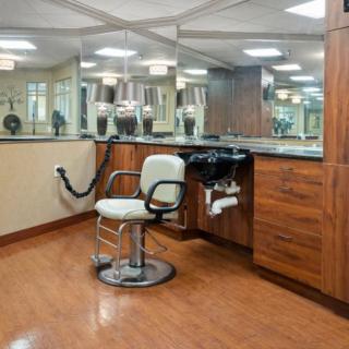 An empty barbershop with a chair and mirrors surrounded by wooden cabinets.