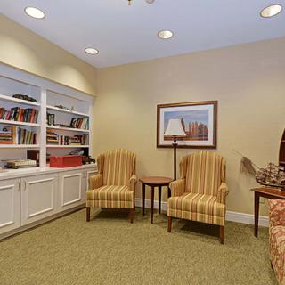 A cozy living room area with two striped chairs, a bookshelf, and a floor lamp.