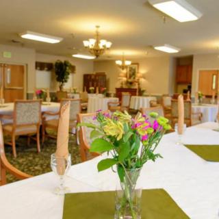 A well-decorated dining room with tables set for a meal, featuring floral centerpieces.