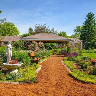 A serene garden pathway surrounded by vibrant flowers and a charming statue, perfect for relaxation.
