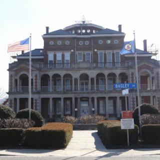 A historical government building featuring a grand architectural design and flags at the forefront.