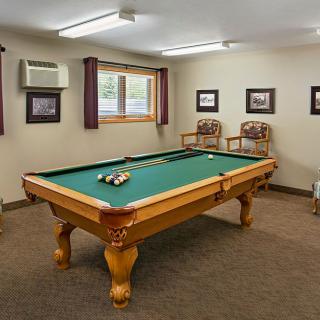A cozy game room featuring a billiards table, chairs, and framed wall art.