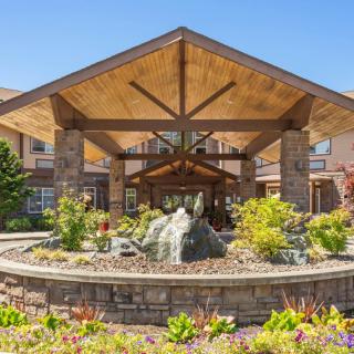 A beautifully landscaped entrance to a modern building with wooden and stone architectural elements.