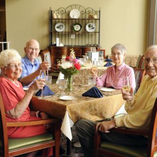 A group of elderly people enjoying a meal together at a dining table.