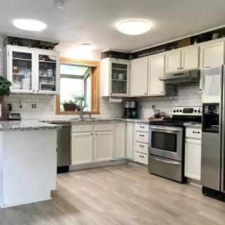 A modern kitchen with white cabinets, stainless steel appliances, and hardwood flooring.